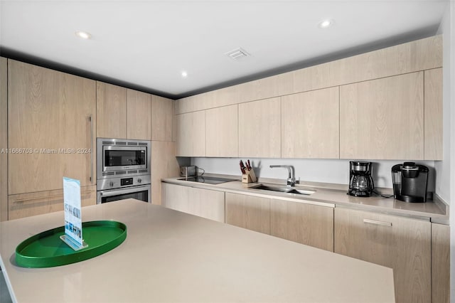 kitchen featuring appliances with stainless steel finishes, modern cabinets, a sink, and light brown cabinetry