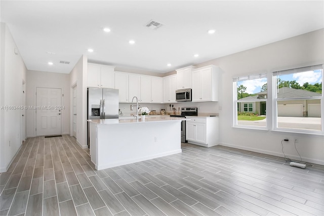 kitchen with white cabinetry, light wood-type flooring, appliances with stainless steel finishes, and a center island with sink