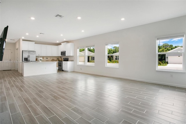 unfurnished living room featuring plenty of natural light and light wood-type flooring