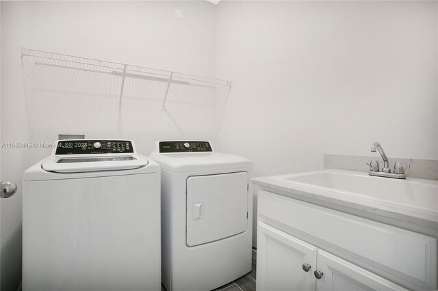 laundry area featuring washer and clothes dryer, cabinets, and sink