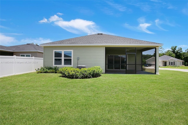 back of property with a sunroom and a yard