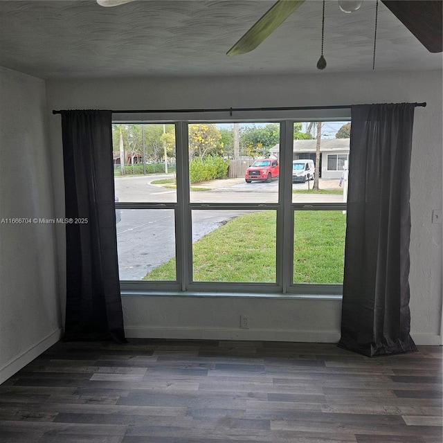 unfurnished room with dark wood-style floors, plenty of natural light, and baseboards