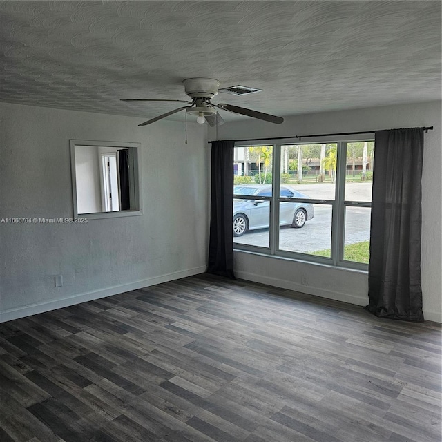 unfurnished room featuring dark wood-style floors, a textured ceiling, and baseboards