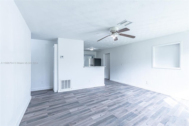 unfurnished living room with a textured ceiling, ceiling fan, and dark wood-type flooring