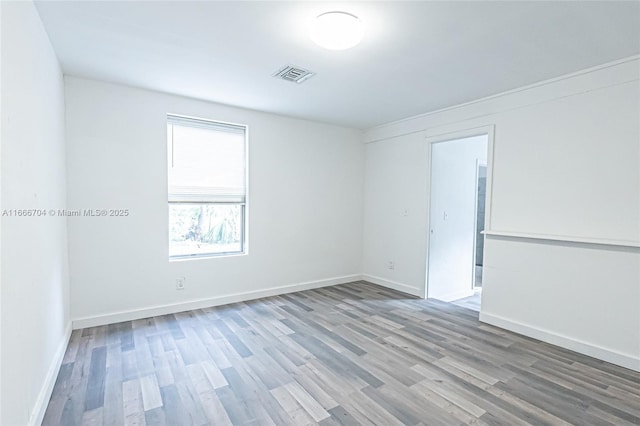 spare room featuring baseboards, visible vents, and wood finished floors