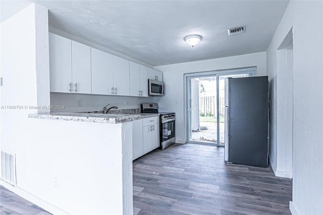 kitchen with kitchen peninsula, dark hardwood / wood-style flooring, white cabinets, and appliances with stainless steel finishes