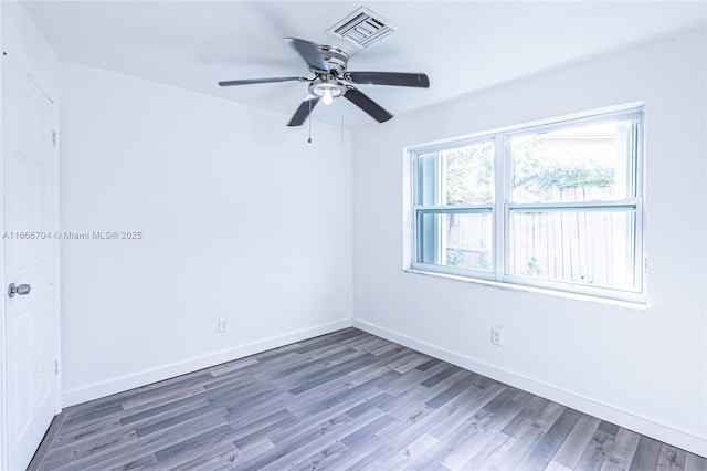 empty room with a ceiling fan, wood finished floors, visible vents, and baseboards