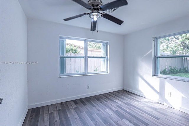 spare room featuring a healthy amount of sunlight, a textured wall, baseboards, and wood finished floors