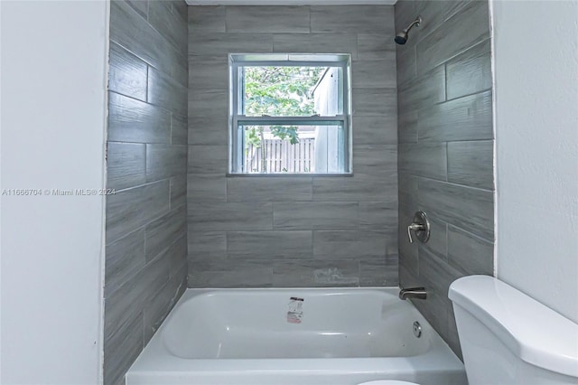 bathroom with tiled shower / bath combo and toilet