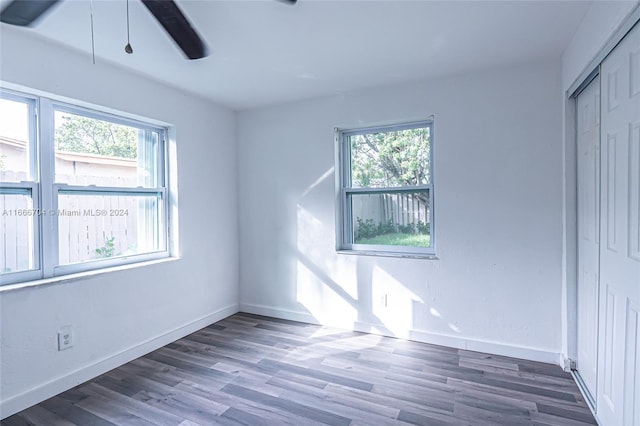 unfurnished bedroom with dark hardwood / wood-style floors, ceiling fan, and multiple windows