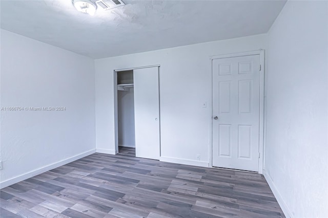 unfurnished bedroom with a closet and dark hardwood / wood-style flooring