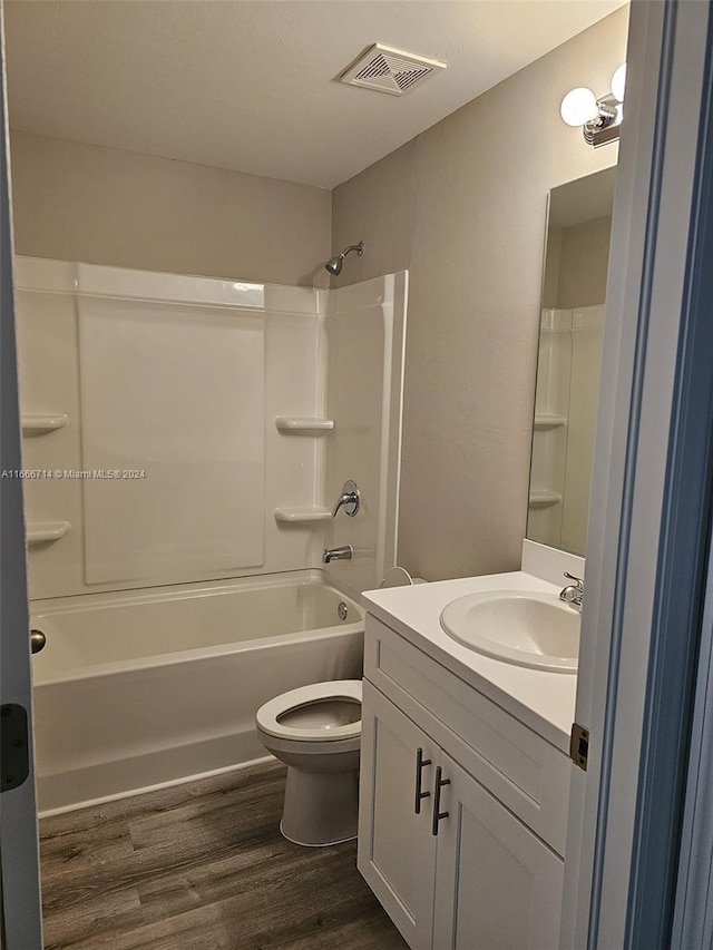 full bathroom with hardwood / wood-style floors, bathing tub / shower combination, vanity, and toilet