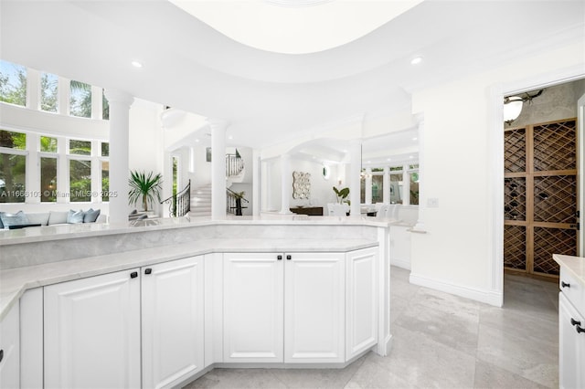 kitchen featuring white cabinetry, kitchen peninsula, and ornate columns