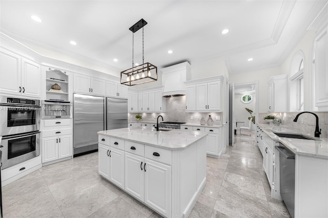 kitchen featuring tasteful backsplash, stainless steel appliances, a kitchen island with sink, sink, and white cabinets