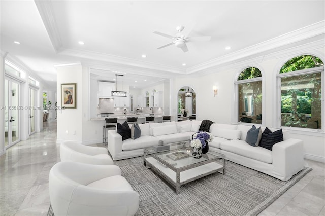 living room with a raised ceiling, ceiling fan, and crown molding