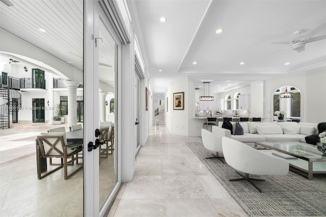 living room featuring a tray ceiling, ceiling fan, ornamental molding, and decorative columns