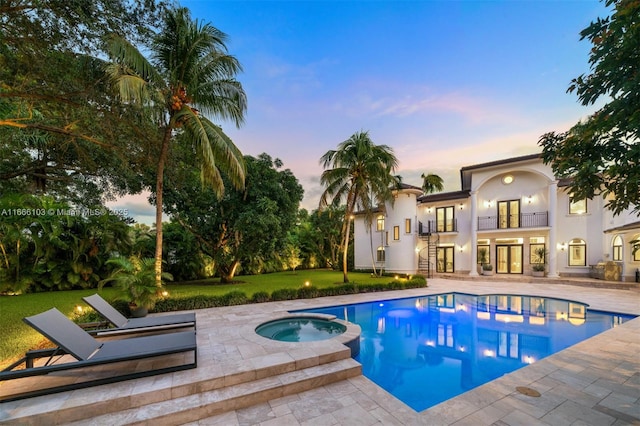 pool at dusk with an in ground hot tub, a yard, and a patio area