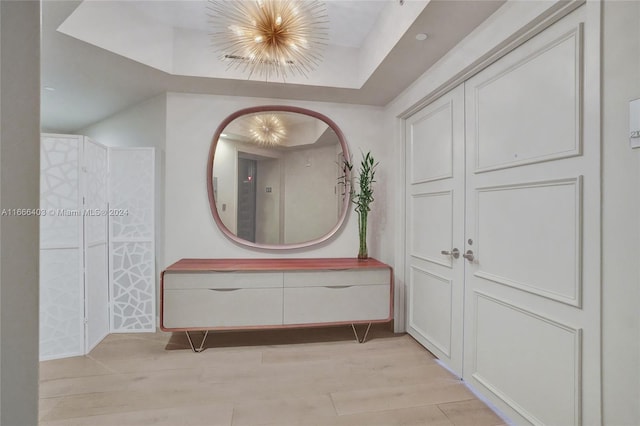 bathroom featuring a tray ceiling, an inviting chandelier, and wood finished floors