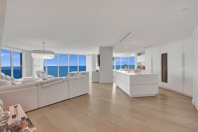 living room featuring light hardwood / wood-style flooring, floor to ceiling windows, a water view, and a healthy amount of sunlight