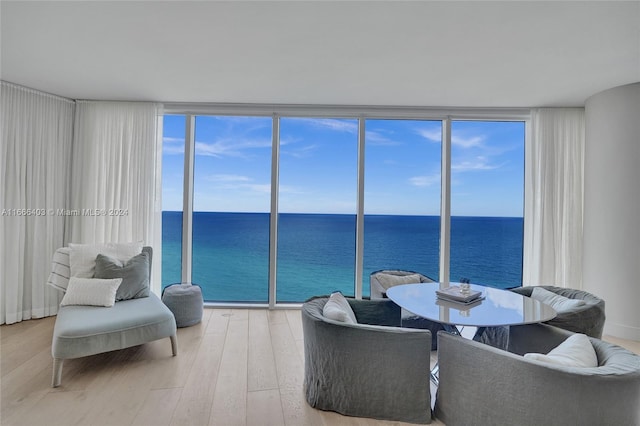 living room with a water view, wood finished floors, and floor to ceiling windows