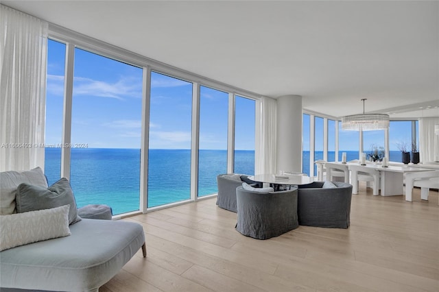 living room featuring light wood-type flooring, a wall of windows, and a water view