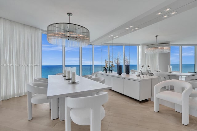 dining room featuring an inviting chandelier, light wood-type flooring, floor to ceiling windows, and a water view