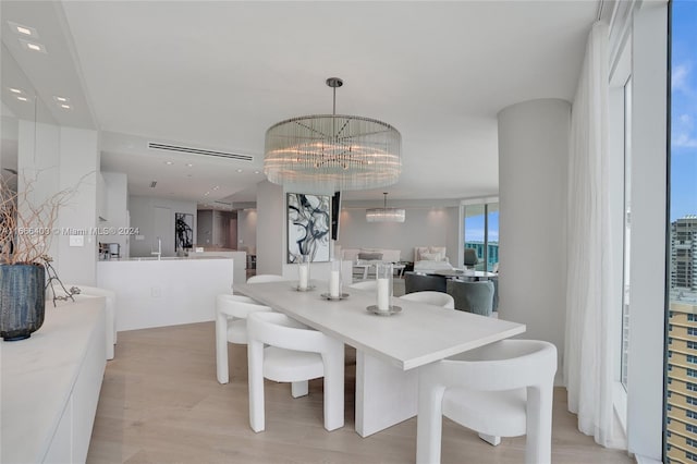 dining area with light wood-type flooring and an inviting chandelier
