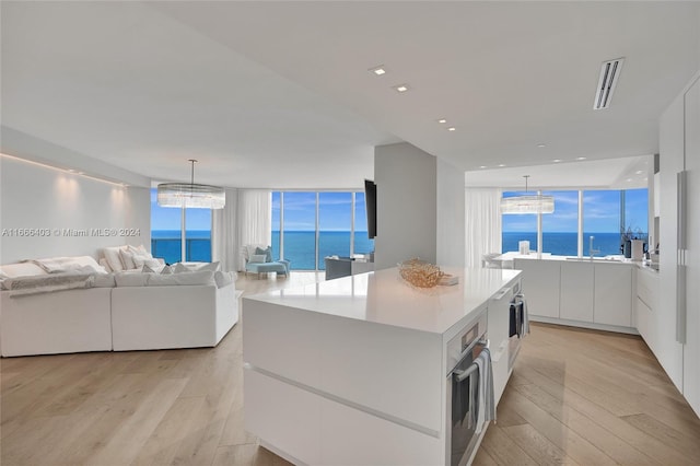 kitchen with a large island, a water view, oven, and white cabinetry