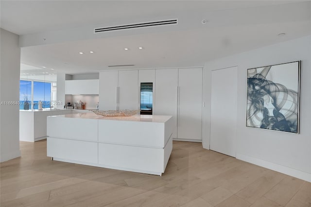 kitchen featuring a center island, modern cabinets, light countertops, white cabinetry, and light wood-style flooring
