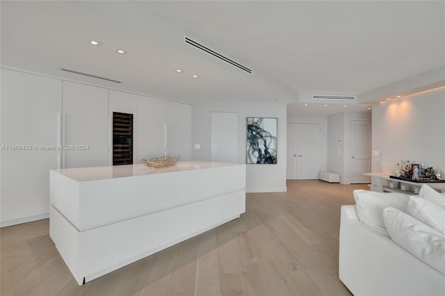 kitchen with a spacious island, light hardwood / wood-style floors, and white cabinetry