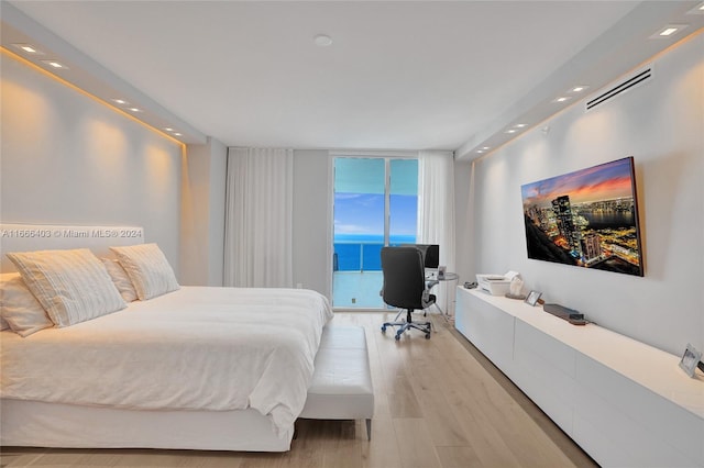 bedroom with access to outside, light hardwood / wood-style flooring, and expansive windows