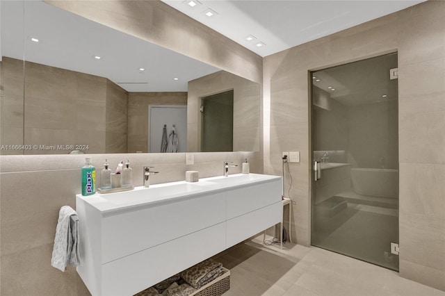 full bath with double vanity, a sink, and tile walls