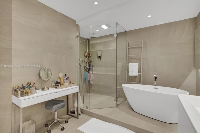 bathroom with tile walls, shower with separate bathtub, and vanity