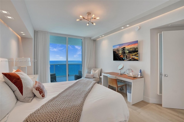 bedroom with a wall of windows, a water view, access to exterior, light hardwood / wood-style flooring, and a notable chandelier