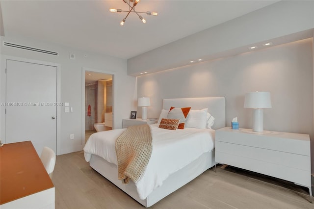bedroom with visible vents, light wood finished floors, ensuite bathroom, and a chandelier