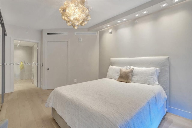 bedroom with light wood-style floors and an inviting chandelier