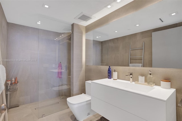 bathroom featuring visible vents, toilet, tile walls, vanity, and a shower with shower door