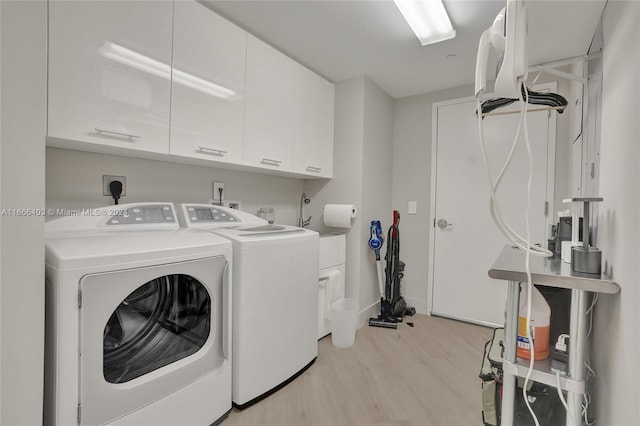 laundry area with light wood finished floors, washer and clothes dryer, and cabinet space