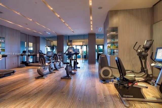 workout area with wooden walls and hardwood / wood-style floors