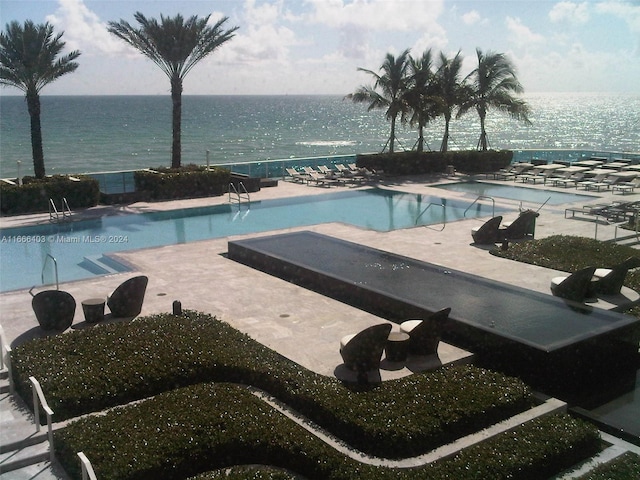 view of pool with a water view and a patio area