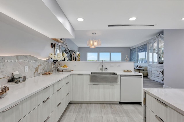 kitchen featuring pendant lighting, dishwasher, tasteful backsplash, sink, and an inviting chandelier