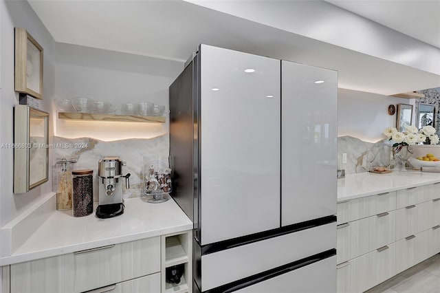 kitchen featuring stainless steel refrigerator, white cabinets, and tasteful backsplash