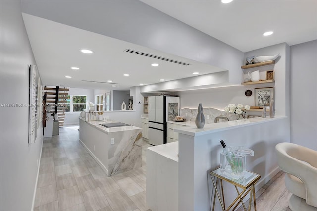 kitchen featuring white refrigerator, white cabinetry, kitchen peninsula, a kitchen island, and black electric cooktop