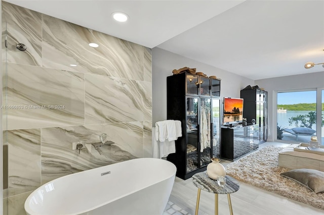 bathroom with a tub to relax in and tile walls