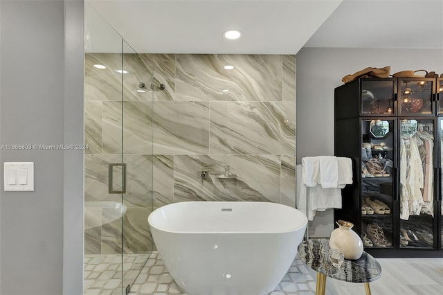 bathroom featuring shower with separate bathtub and tile walls