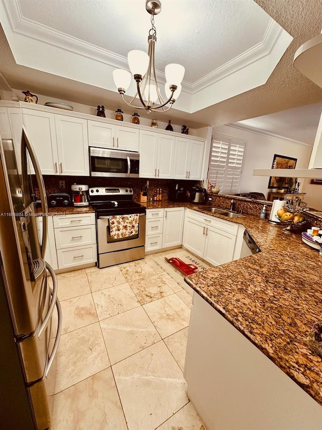 kitchen with pendant lighting, a raised ceiling, tasteful backsplash, a textured ceiling, and stainless steel appliances