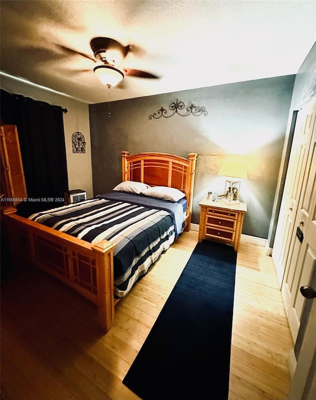 bedroom with light hardwood / wood-style floors, ceiling fan, and a closet