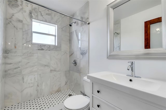 bathroom with vanity, toilet, and a tile shower