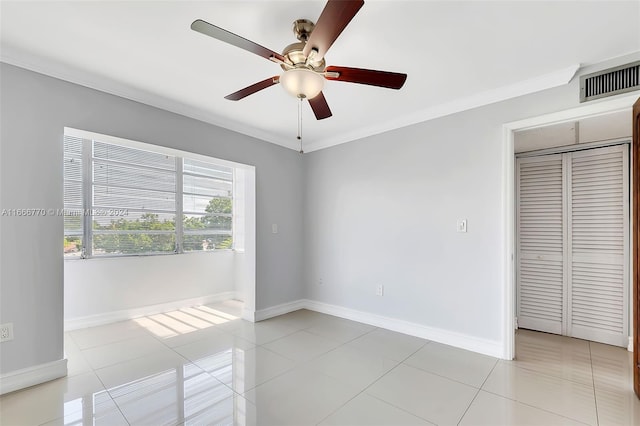 spare room with ceiling fan, light tile patterned floors, and crown molding