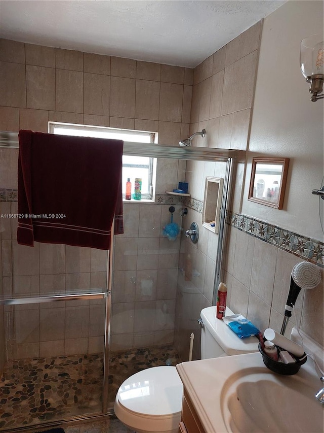 bathroom with walk in shower, vanity, tile walls, and toilet